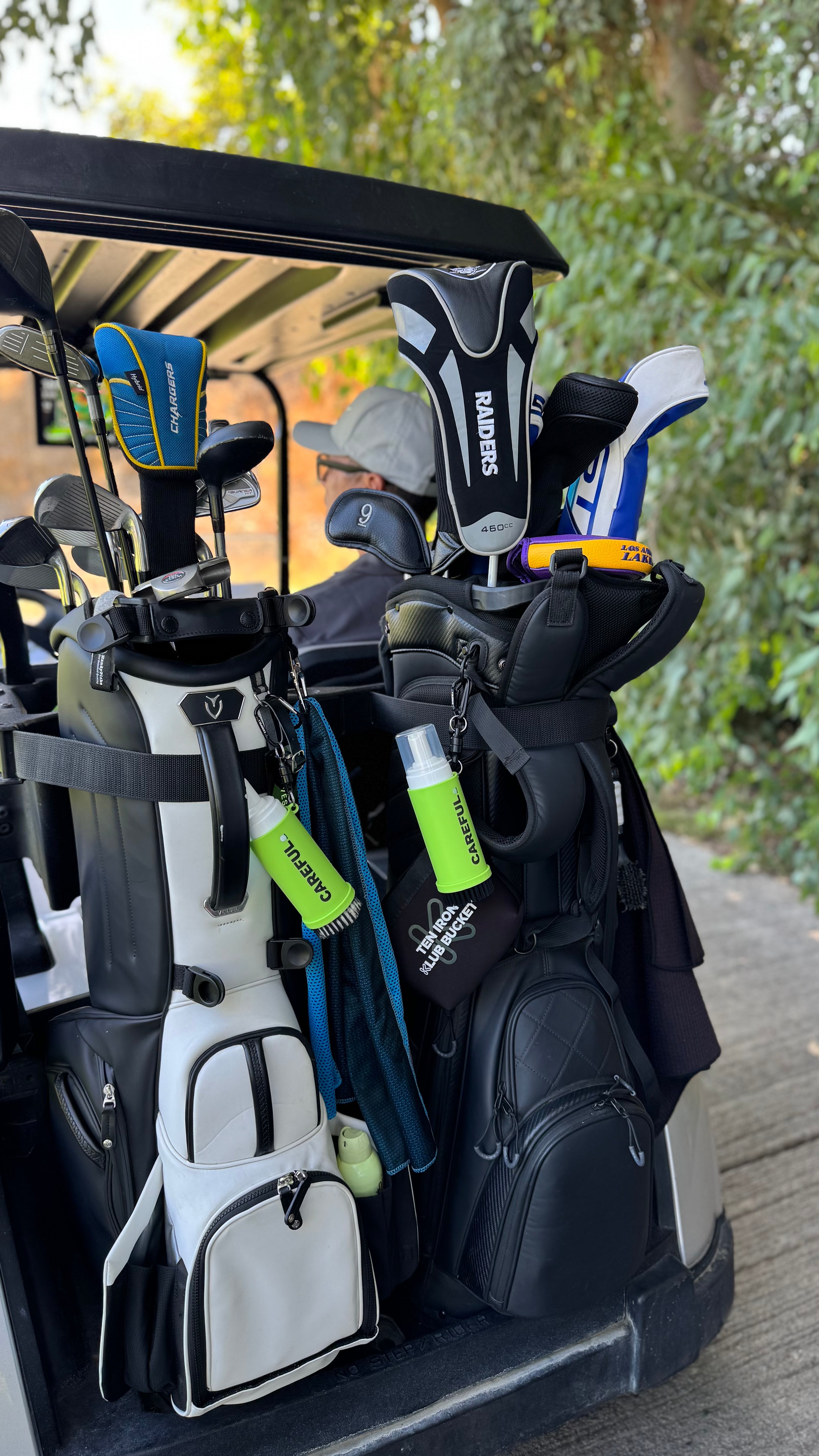 Careful Golf Cleaner hanging on each golf bag strapped onto the back of a golf cart with a full set of clubs